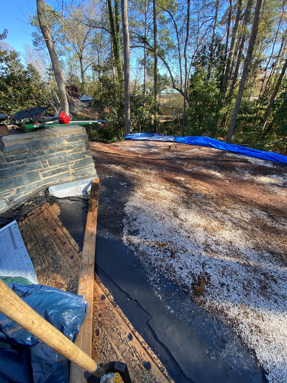 Existing worn roof surface beside the stone chimney, before new shingles were installed.